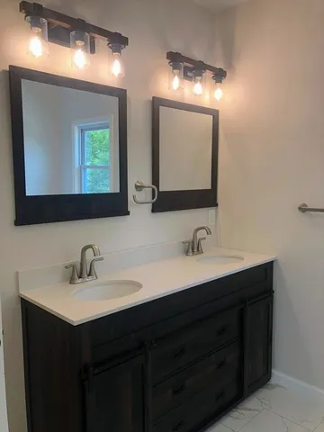 a bathroom with double sink and two mirror