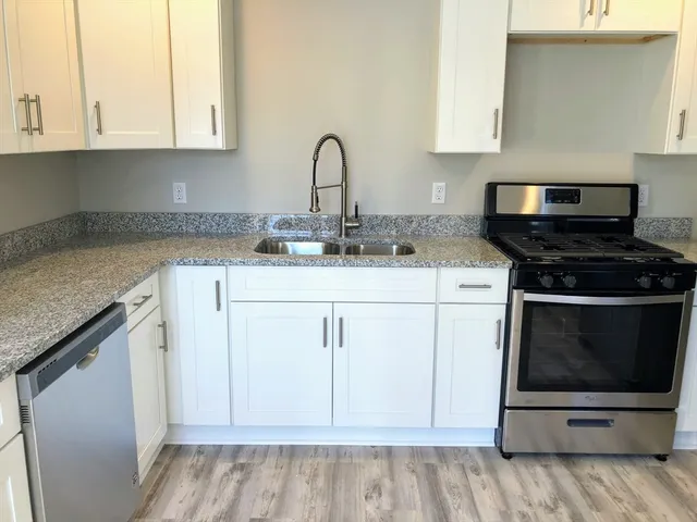 a kitchen with granite countertop white cabinets and black appliances