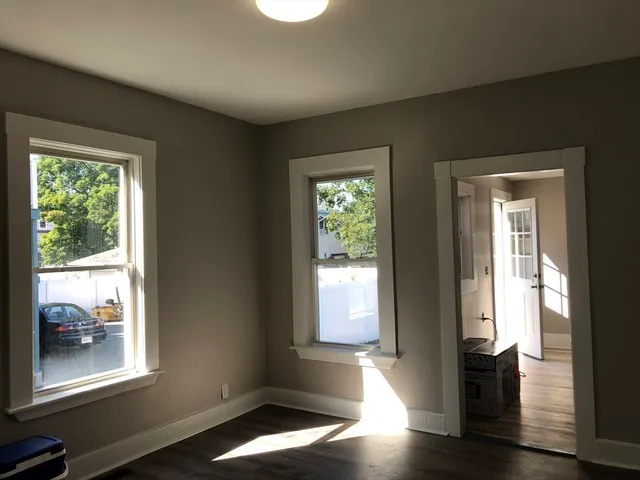 a view of an empty room with wooden floor and a window