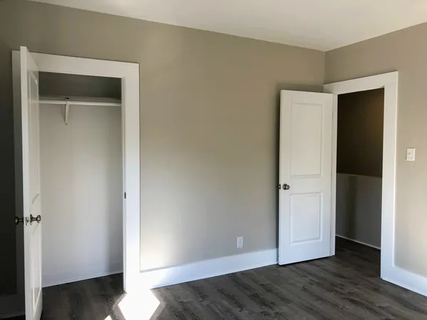 a view of an empty room with wooden floor & closet