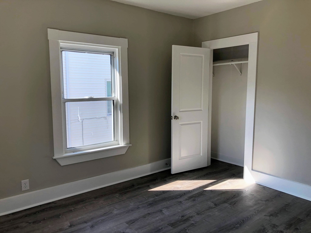 28-32 Calvary Street Waltham, MA 02453 - Photo 28 of 41 an empty room with wooden floor cabinet and windows