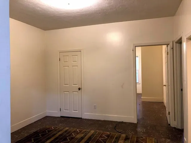 an empty room with wooden floor and entrance door