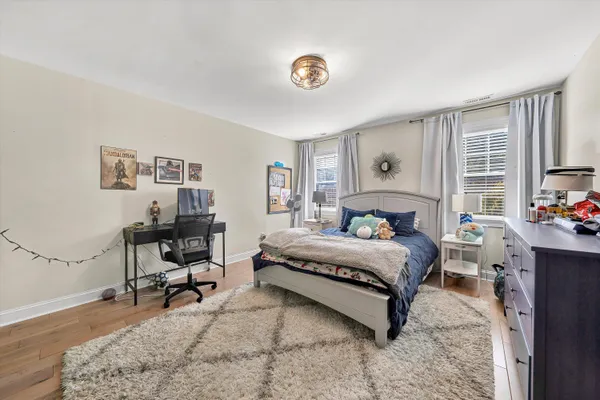 a spacious bedroom with a bed a table chair and a window