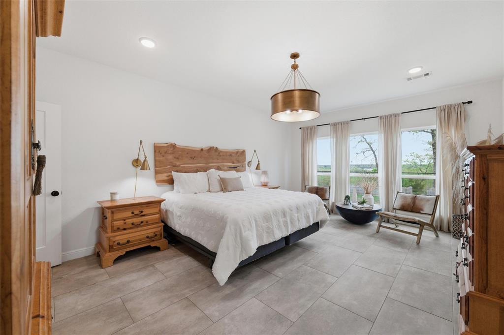 434 Sandstone Court Sunset, TX 76270 - Photo 18 of 40 a spacious bedroom with a bed and a chandelier