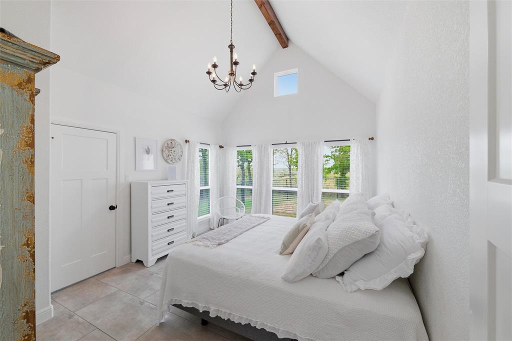 434 Sandstone Court Sunset, TX 76270 - Photo 25 of 40 a bedroom with a large bed and a chandelier