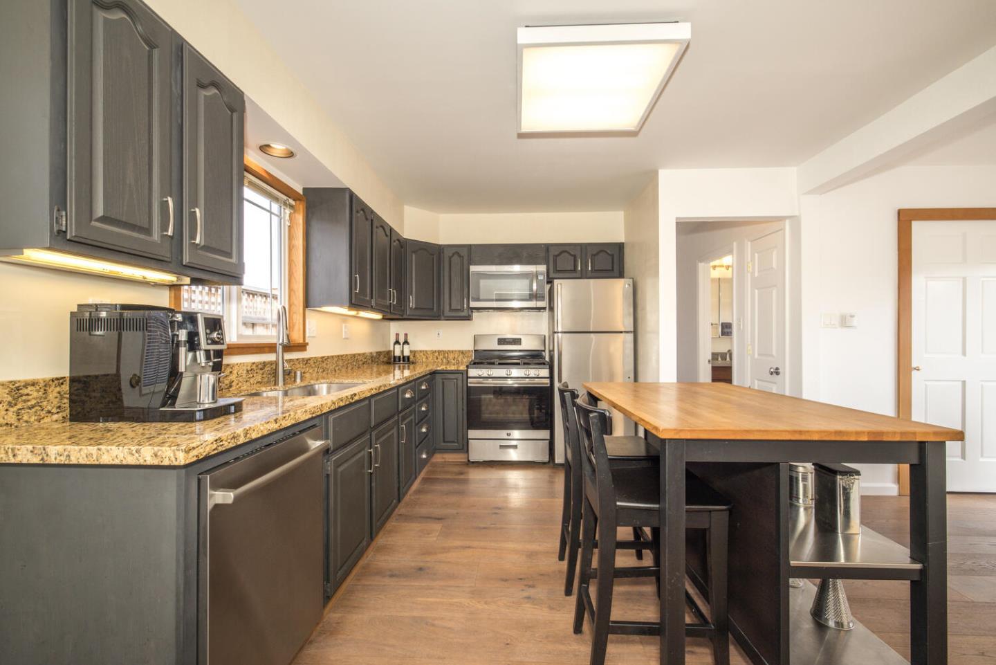365 Spruce Street Half Moon Bay, CA 94019 - Photo 5 of 34 a kitchen with stainless steel appliances granite countertop a stove top oven a sink dishwasher a dining table and chairs with wooden floor
