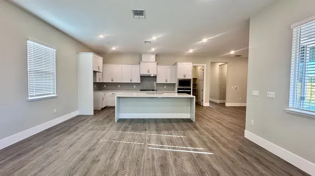 a large kitchen with kitchen island a counter top space a sink stainless steel appliances and cabinets