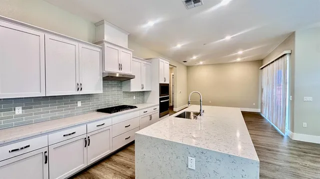 a kitchen with granite countertop a sink stainless steel appliances and cabinets
