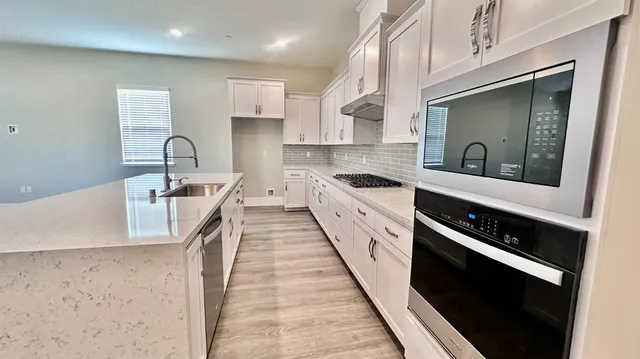 a kitchen with stainless steel appliances a sink a stove top oven a counter space and cabinets