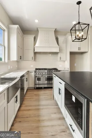 a large kitchen with stainless steel appliances granite countertop a sink a stove and a wooden floors