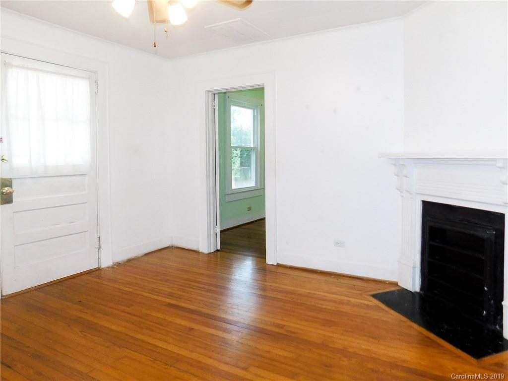 6201 Rumple Road Charlotte, NC 28262 - Photo 4 of 22 an empty room with wooden floor fireplace and windows