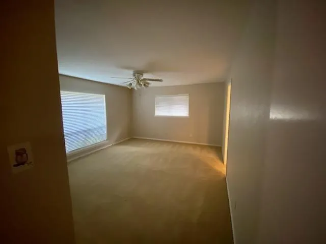 an empty room with windows and chandelier fan