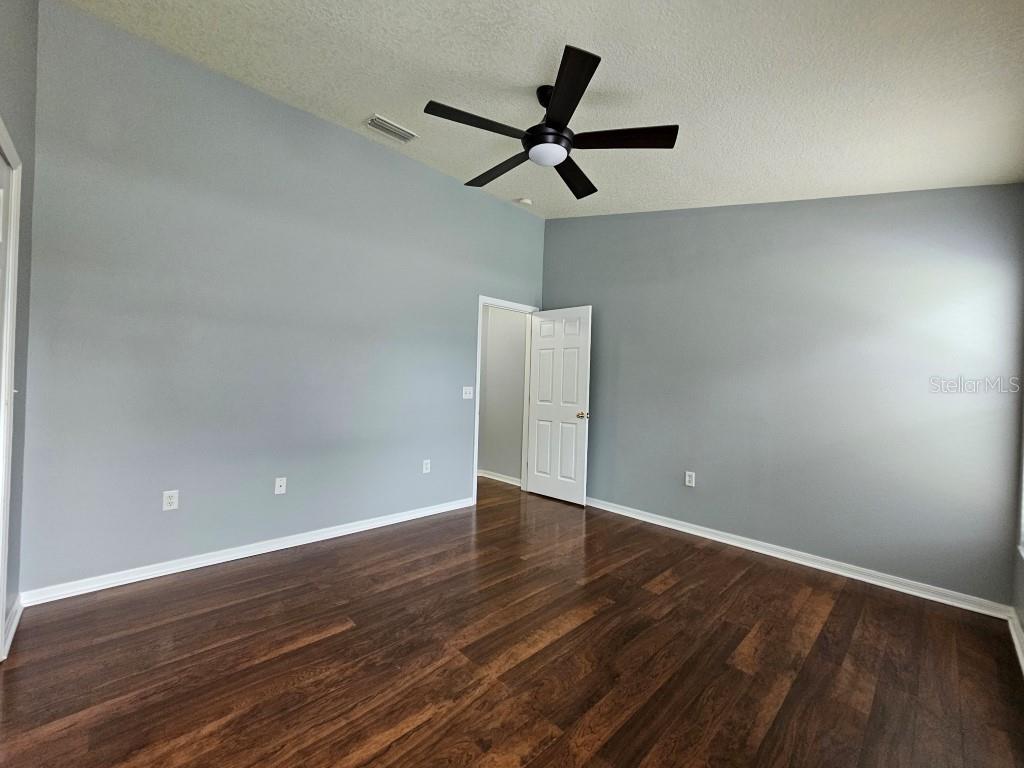 1404 Blue Magnolia Road Brandon, FL 33510 - Photo 18 of 21 a view of an empty room with wooden floor and a ceiling fan