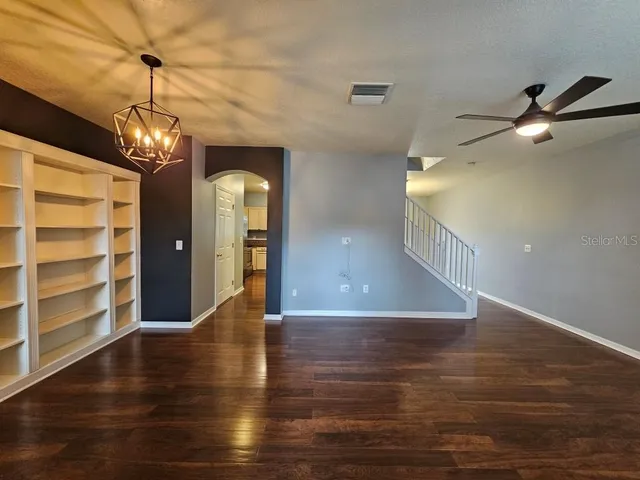 a view of a hallway with wooden floor and a chandelier