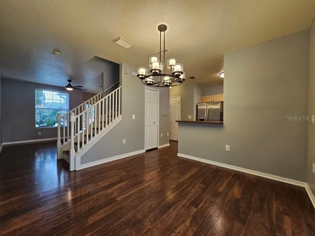 a view of a livingroom with wooden floor staircase and a chandelier