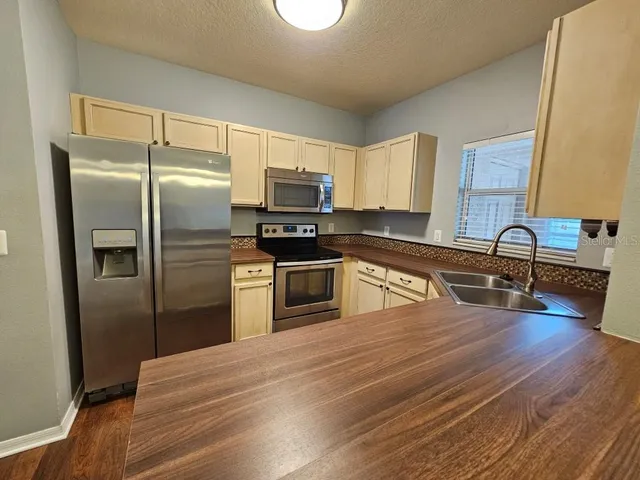 a kitchen with granite countertop a refrigerator and a stove top oven