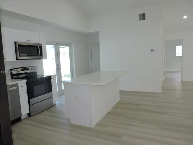 a view of a kitchen with a refrigerator a microwave and a sink