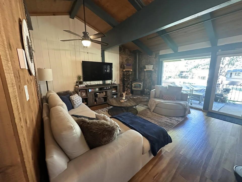 3252 Chateau Road, Unit 43 Mammoth Lakes, CA 93546 - Photo 7 of 29 Vaulted wood-finish ceiling with exposed beams, wood-finish flooring, stone-clad fireplace with wood-burning stove, and a wall of glass doors