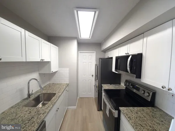 a kitchen with granite countertop a sink stove and cabinets