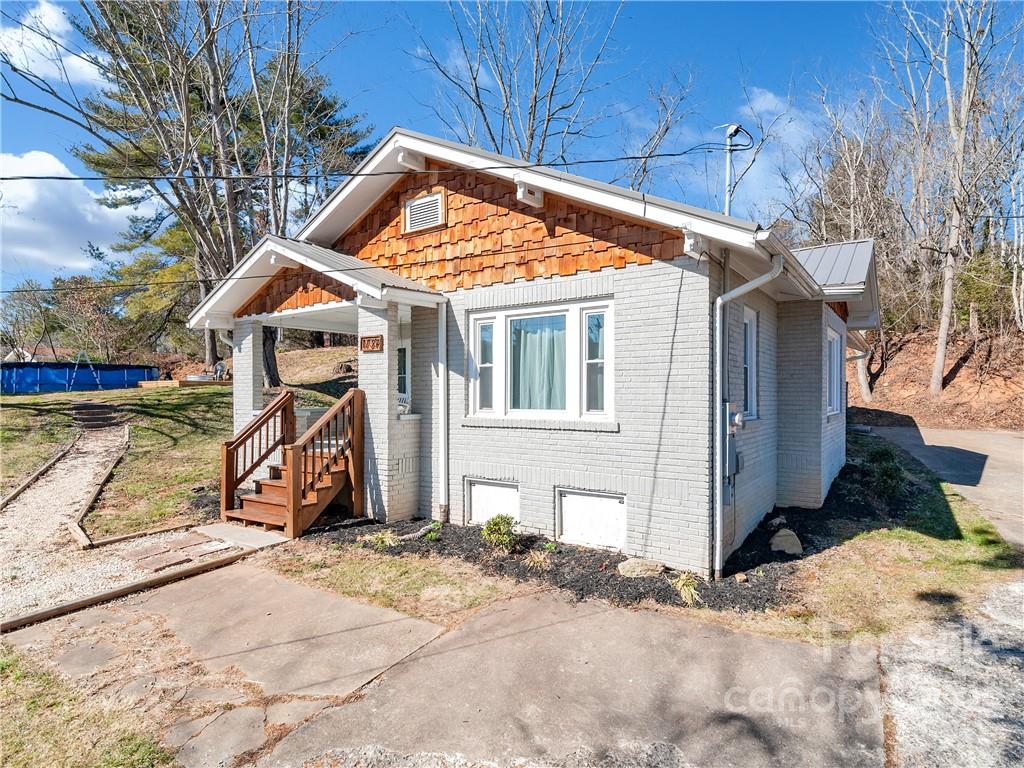 a view of a wooden house with a yard and large tree