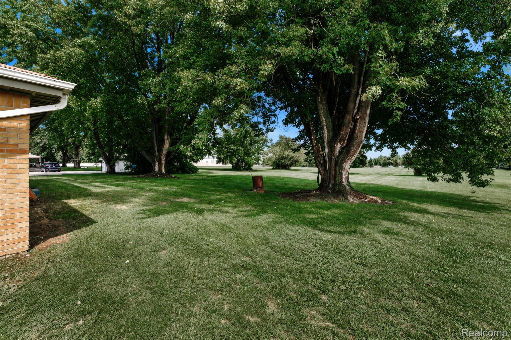 4499 South Linden Road Flint, MI 48507 - Photo 30 of 36 Expansive grassy yard with mature trees, a brick exterior, and white gutters