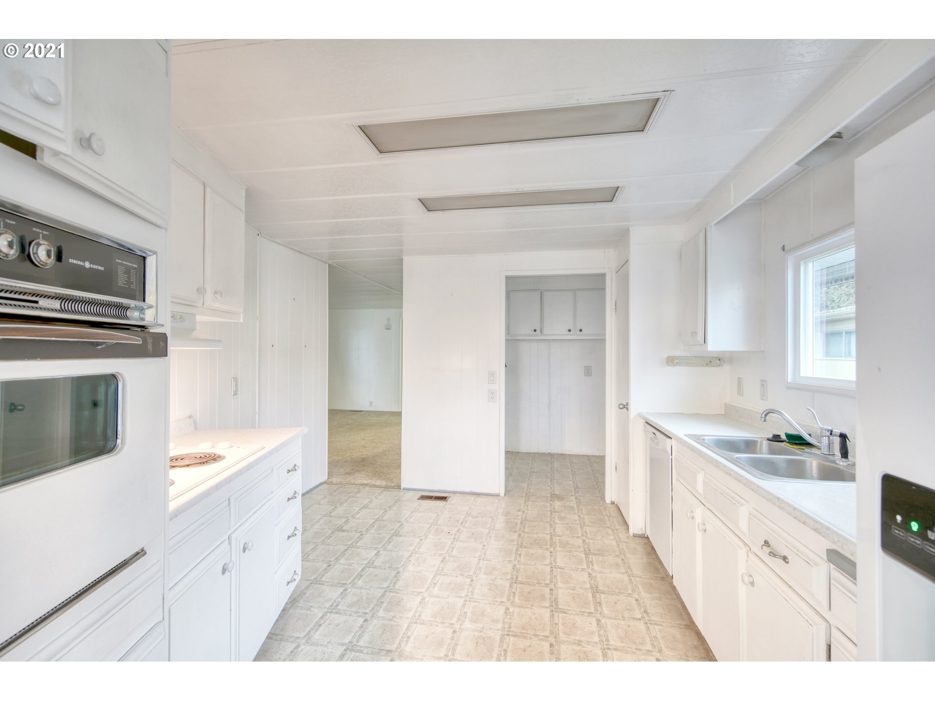 3530 Game Farm Road, Unit 46 Springfield, OR 97477 - Photo 17 of 32 a large white kitchen with granite countertop a sink and dishwasher a stove top oven with wooden floor