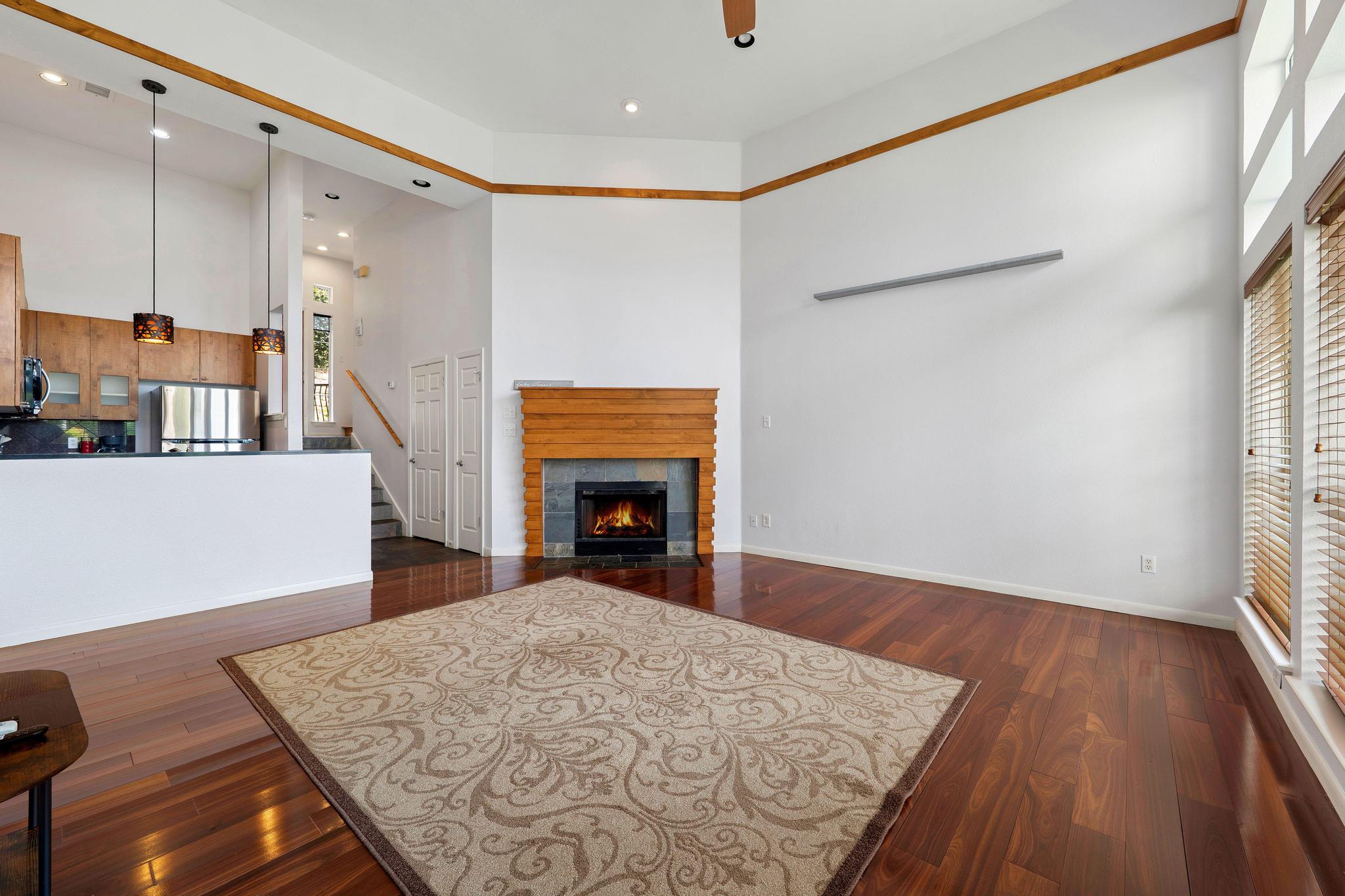 2918 Ranch Road 620, Unit J162 Austin, TX 78734 - Photo 13 of 26 Spacious living area featuring high ceilings, wood-finish flooring, a contemporary fireplace with a wood mantle, and abundant natural light from tall windows