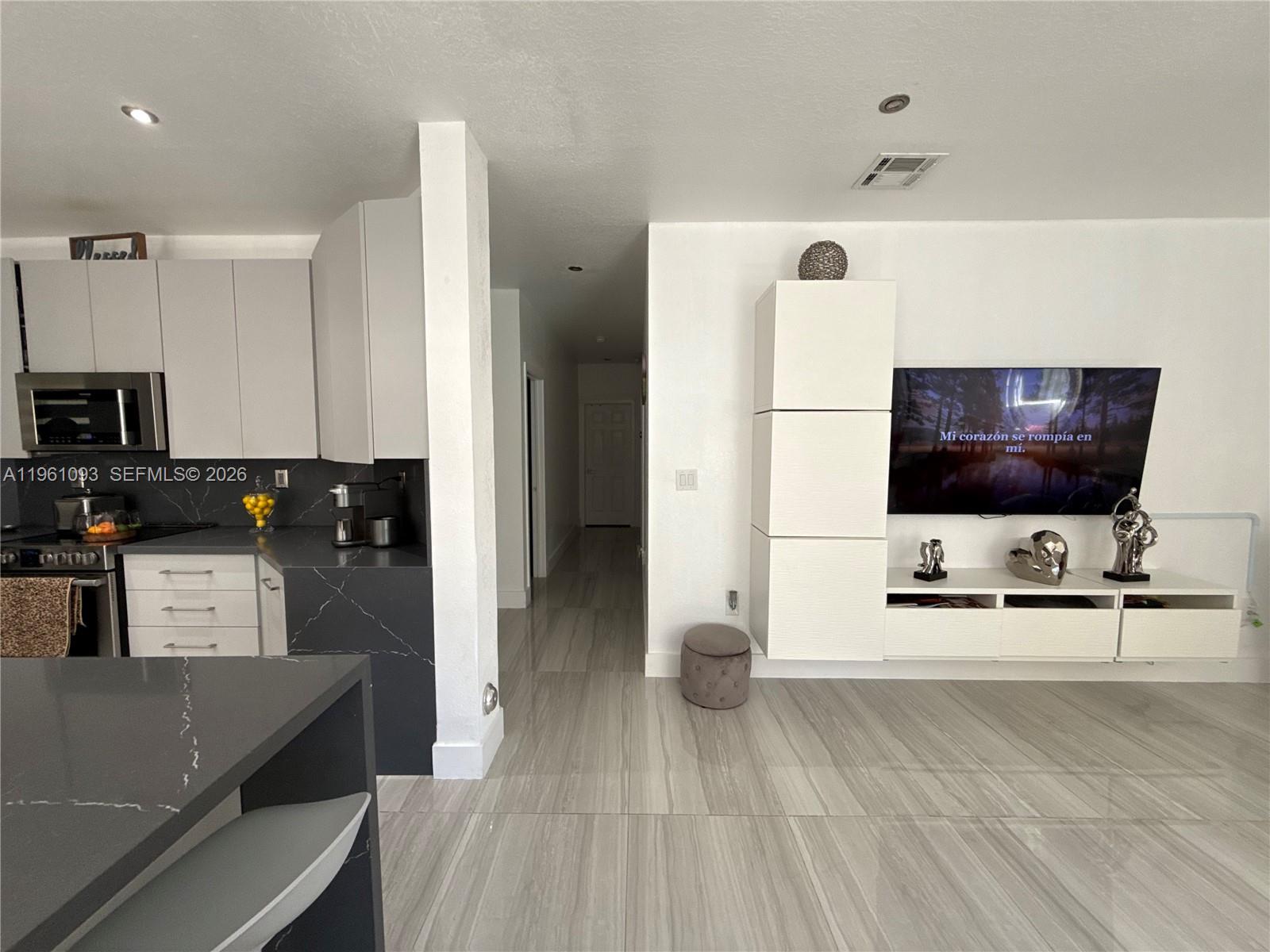 14214 Southwest 289th Terrace Homestead, FL 33033 - Photo 7 of 13 a living room with stainless steel appliances a flat screen tv and a refrigerator