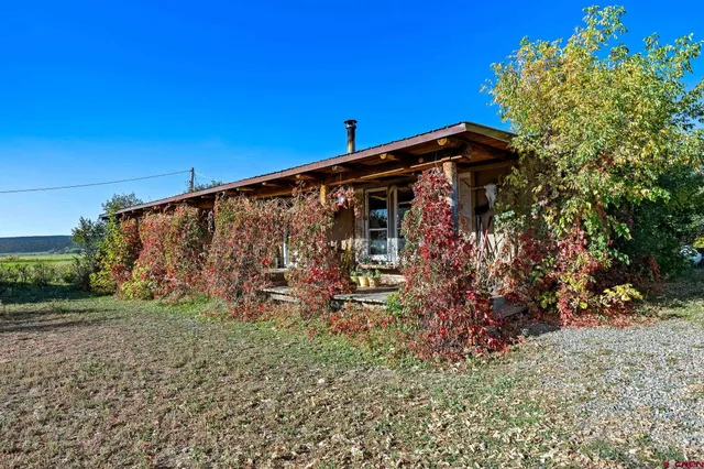 a view of a small barn with a big yard and large trees