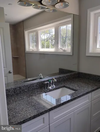 a bathroom with a granite countertop sink and window