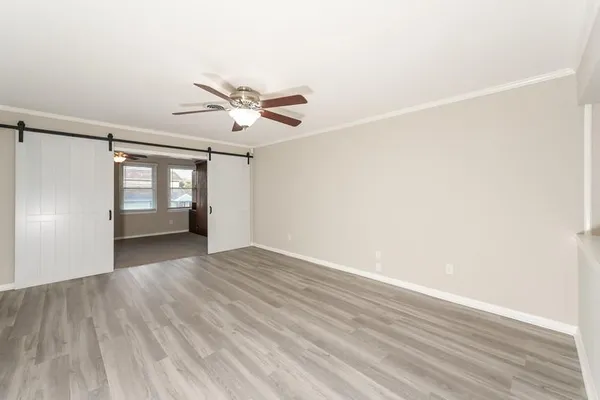 a view of empty room with wooden floor and fan