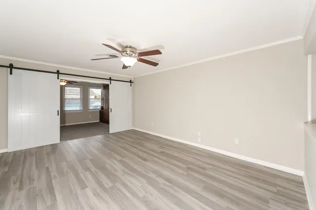 a view of empty room with wooden floor and fan