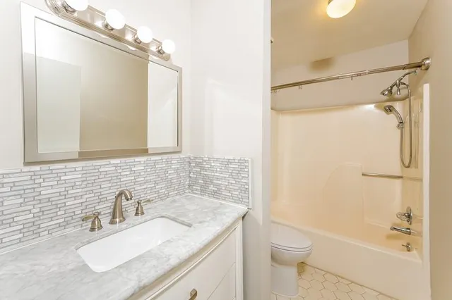 a bathroom with a granite countertop sink toilet and shower