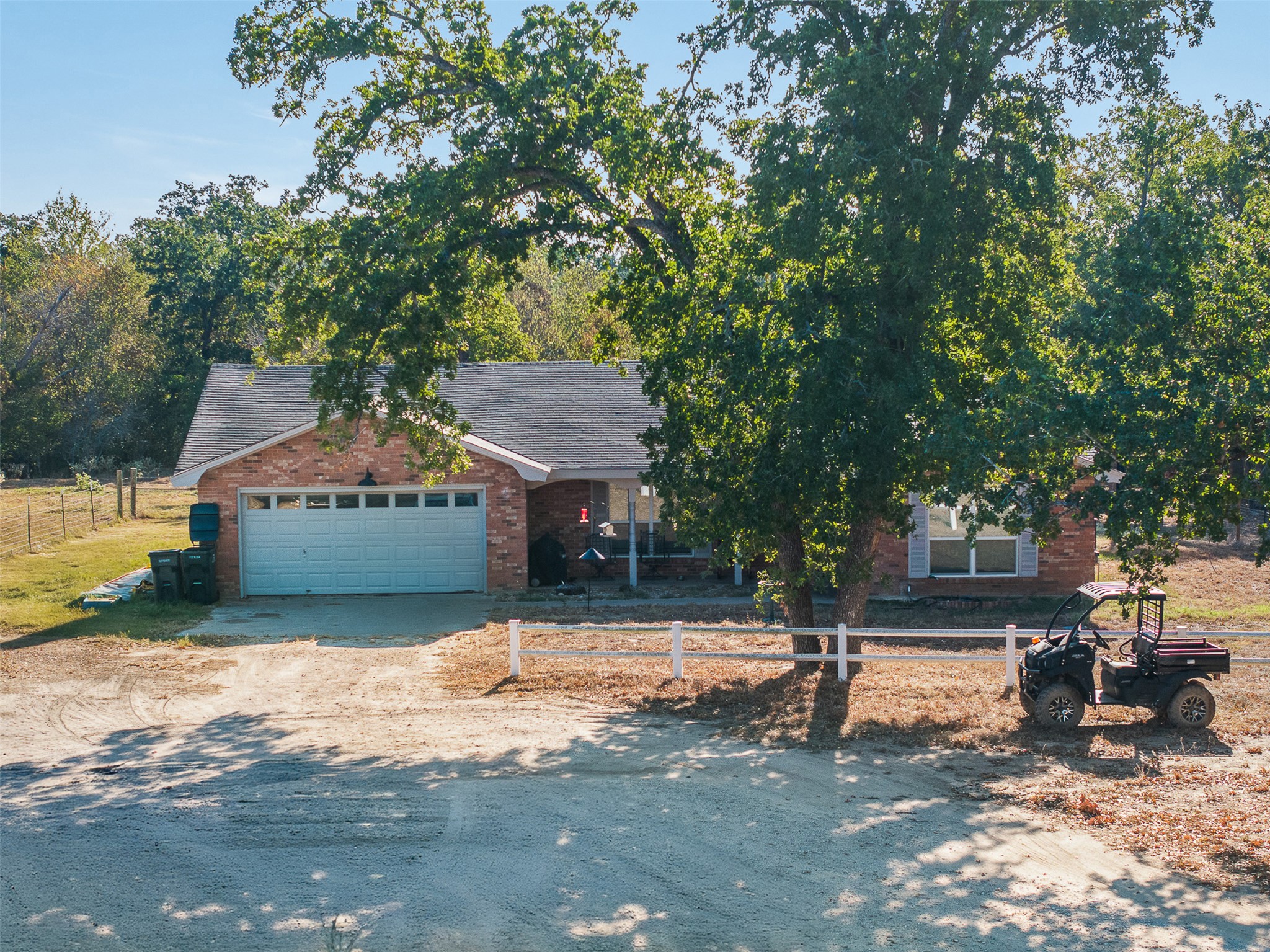 139 Farm To Market 696 Elgin, TX 78621 - Photo 27 of 27 View of front of home with driveway, a fenced front yard, brick siding, a garage, and roof with shingles