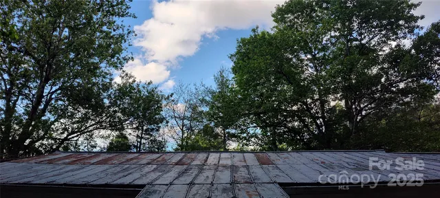 a view of barn with wooden fence and large trees
