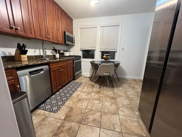 a kitchen with granite countertop a sink a stove top oven a dining table and chairs