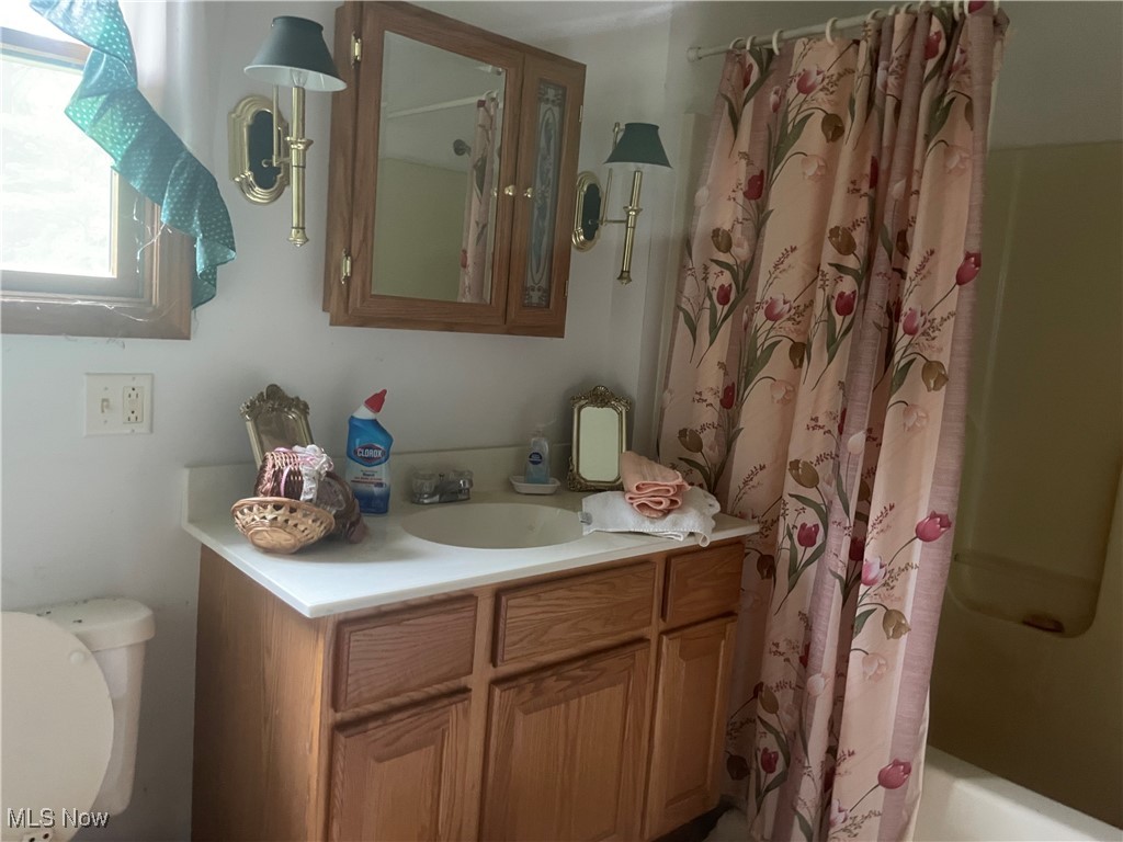 Full bath featuring vanity, toilet, and shower / bathtub combination with curtain