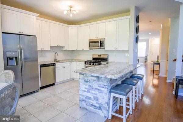 a large kitchen with kitchen island granite countertop a table and chairs in it