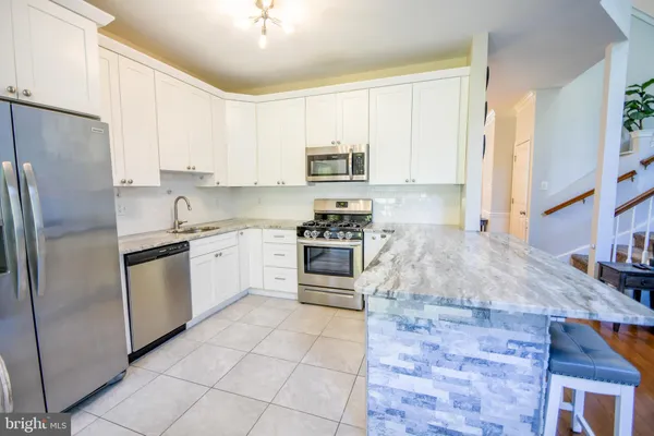 a kitchen with stainless steel appliances granite countertop a sink stove refrigerator and cabinets