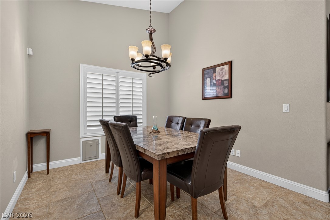 818 Manor Shores Road Henderson, NV 89002 - Photo 8 of 35 A striking chandelier hangs above a dining table set with six chairs, ready for memorable meals.