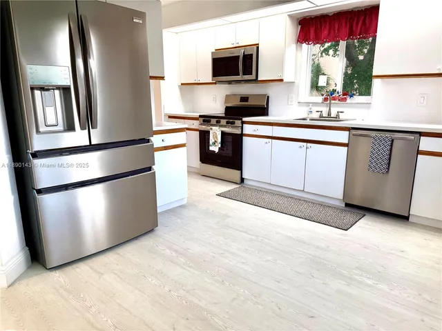 a kitchen with stainless steel appliances granite countertop a refrigerator a stove a sink and a microwave