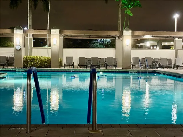 an aerial view of a swimming pool with a yard and seating area