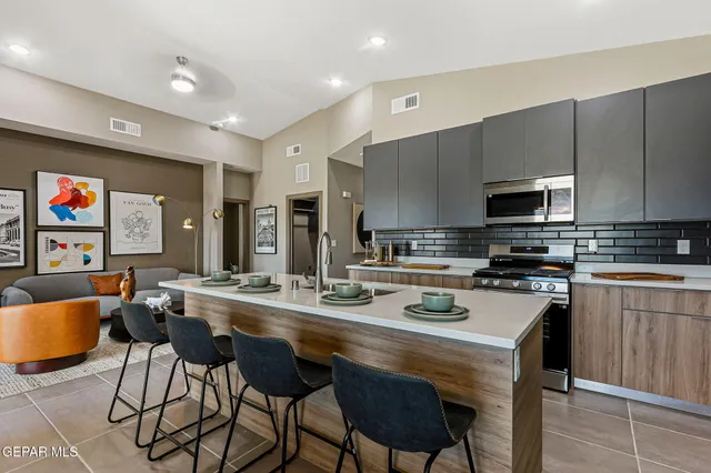 a kitchen with stainless steel appliances a stove a sink a microwave a refrigerator and chairs