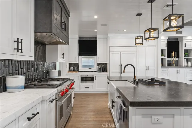 a kitchen with stainless steel appliances granite countertop a sink a stove and a wooden floors