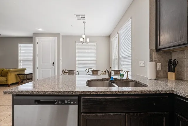 a kitchen with granite countertop a sink stainless steel appliances and cabinets