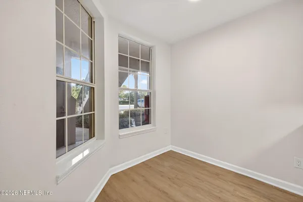 a view of an empty room with wooden floor and a window