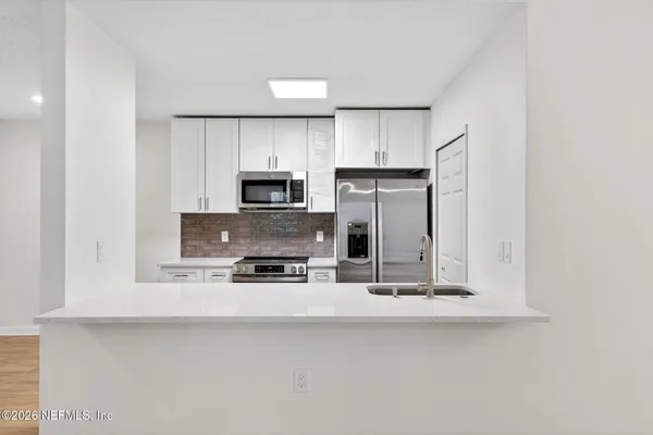 a kitchen with stainless steel appliances a stove top oven a sink and a refrigerator