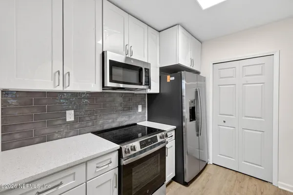 a kitchen with stainless steel appliances white cabinets and a stove top oven