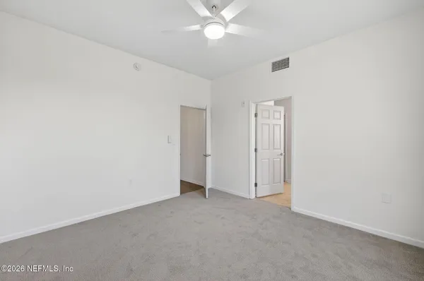 an empty room with closet and a ceiling fan