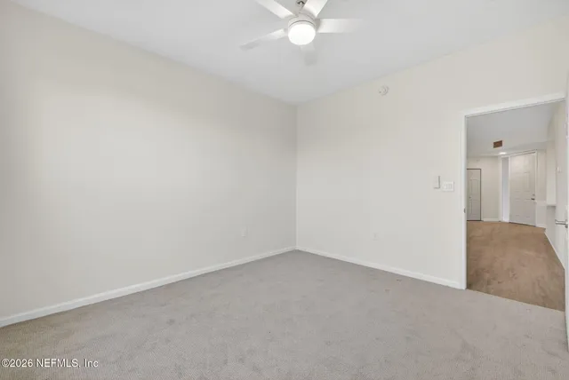 an empty room with a chandelier fan and closet